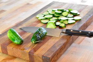 sliced cucumbers on cutting board with chef's knife