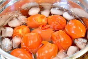 tomatoes in an ice bath with the skins beginning to peel