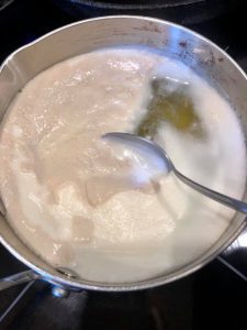 pot of mushroom broth simmering, spooning off foam