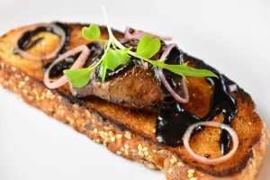 seared goose liver on toast with dark berry drizzle and shallot rings