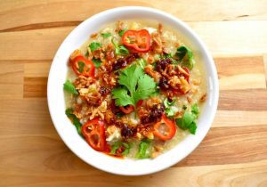 bowl of turkey congee topped with chili oil, red peppers, and cilantro
